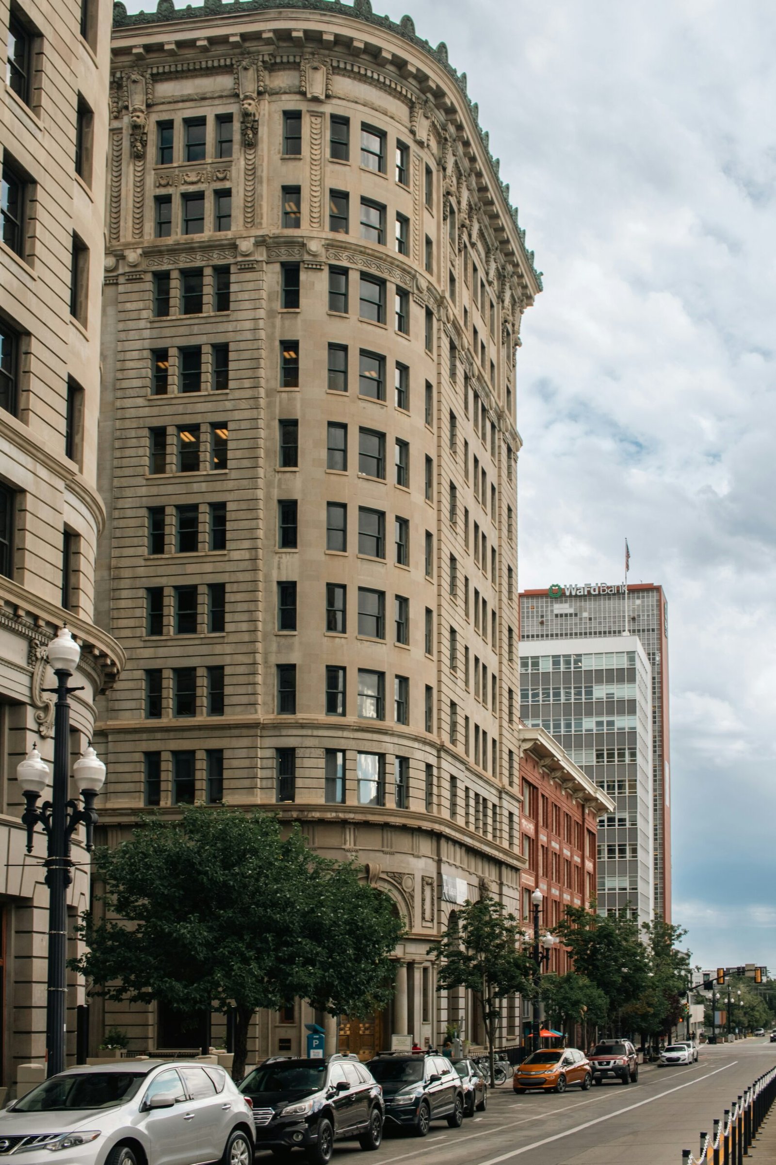 A city street lined with tall buildings and parked cars